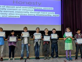 students standing in front of stage with certificate in hands 